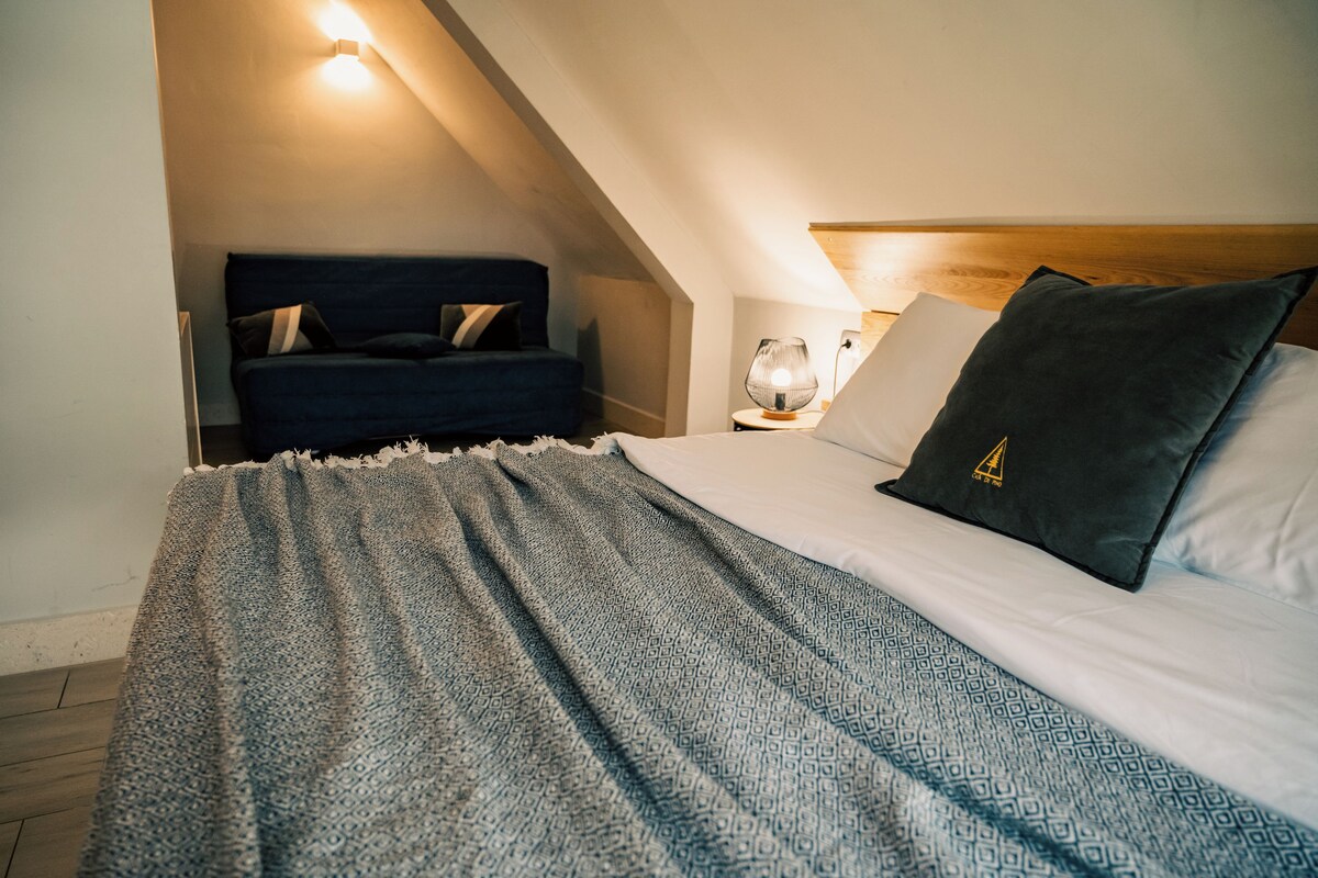Ein Schlafzimmer mit einem Bett, einer dunkelblauen Kopfteil, einer gemusterten Decke und einem Nachttisch mit einer Lampe.