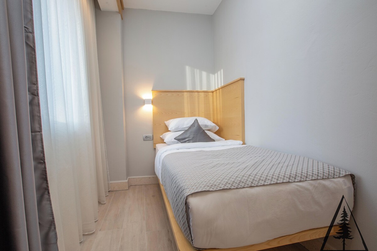 A neatly arranged bedroom with a wooden headboard, a bed with a patterned bedspread, and a bedside lamp.