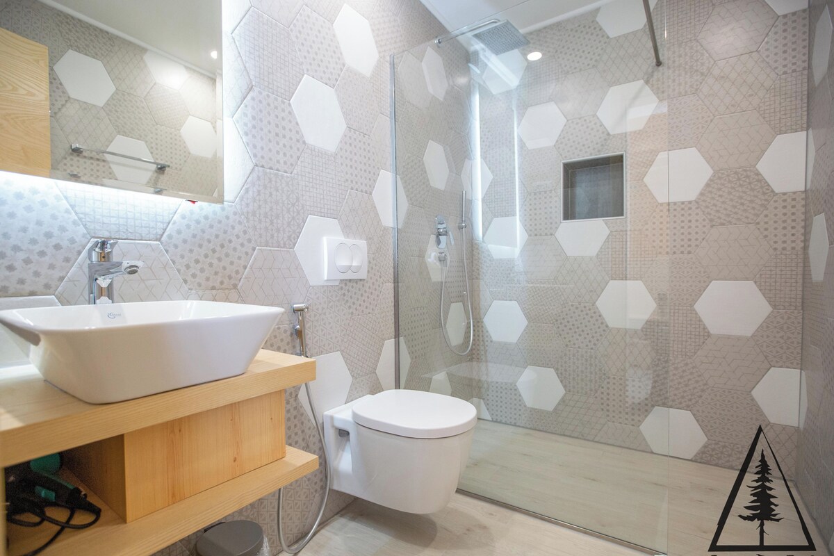 Une salle de bain moderne avec un grand lavabo blanc, des toilettes et une douche séparée par une paroi de verre.