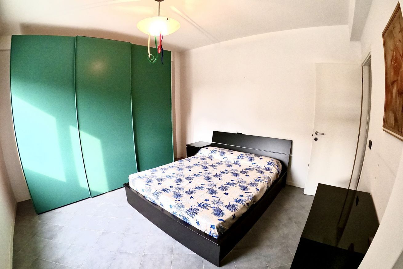 Un dormitorio con cama, armario, mesita de noche y puerta.