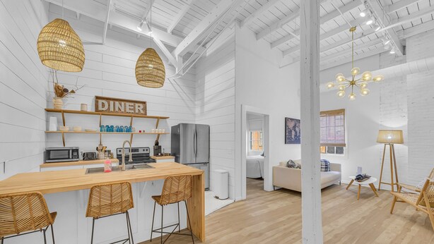 A modern kitchen with a wooden island, bar stools, and a 'DINER' sign. - The Dawg Walk Downtown (Athens)
