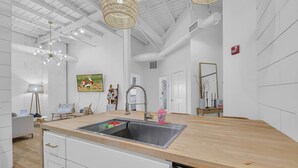 A modern kitchen with a large island, white cabinetry, and a stainless steel sink. - The Dawg Walk Downtown (Athens)