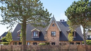 A large, two-story house with a steeply pitched roof, brick exterior, and a stone foundation. - Landhaus Senwai 3 - Neubau. Stadtnah. Wellness (Sylt)