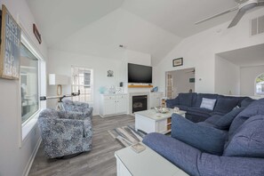 A spacious living room with a large sofa, a television, and a fireplace.