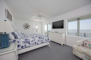 A bedroom with a bed, a dresser, a TV, and a window with a view.