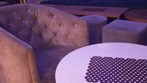 A seating area with a tufted armchair and a round table with a geometric pattern. - Crale n Busino (Port Harcourt)