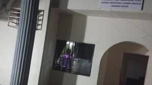 A room with a blue table, a window with metal bars, a sign for 'CRALE & BUSINO HOTEL' listing amenities like a restaurant and laundry services, and a tiled floor. - Crale n Busino (Port Harcourt)