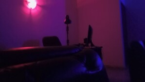 A dimly lit room with a single chair, a desk with a computer, and a wall-mounted lamp. - Crale n Busino (Port Harcourt)