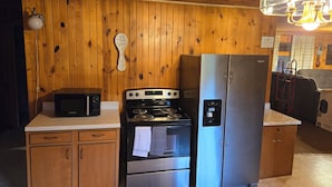 A compact kitchen with wooden walls, a stove, a refrigerator, and a microwave. - Lake front suite on very desirable lake in Gwinn, Mi. Year round activities. (Gwinn)