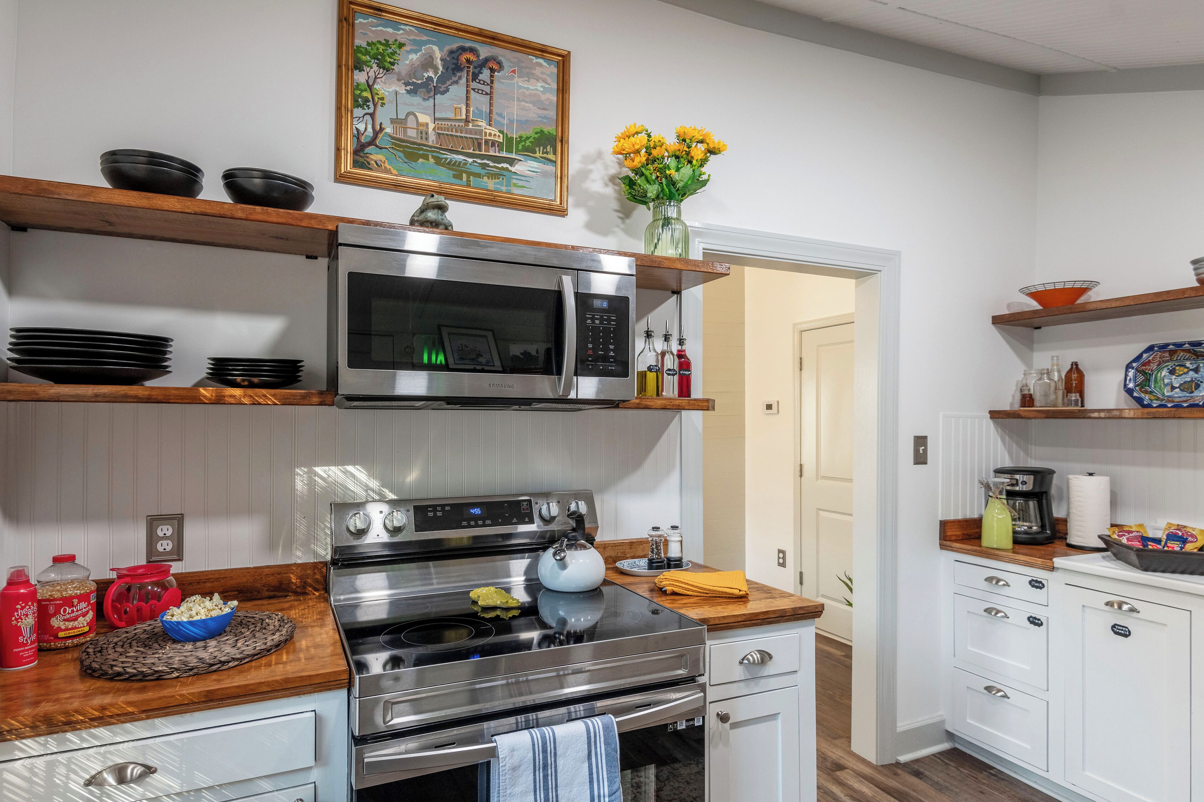 Une cuisine moderne équipée d’une cuisinière, d’un four à micro-ondes et d’étagères en bois, le tout en acier inoxydable.