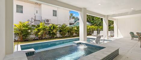 A modern indoor swimming pool with clear blue water, surrounded by white walls and a tiled deck.