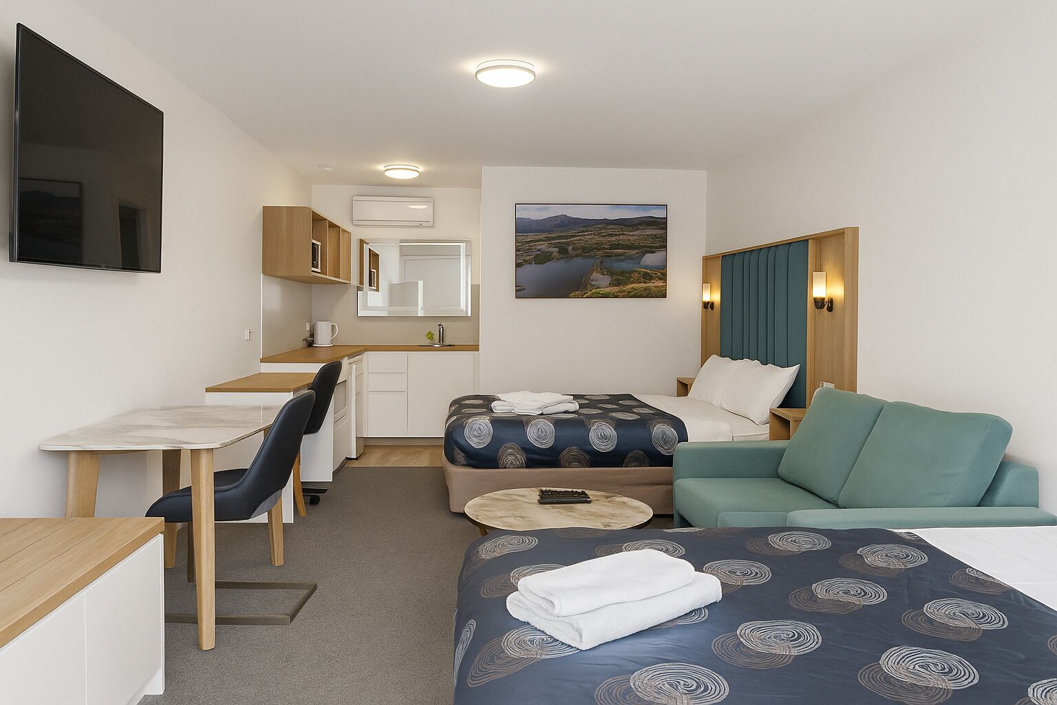 Une chambre d’hôtel de taille réduite, comprenant un lit, un canapé, un bureau et une kitchenette.
