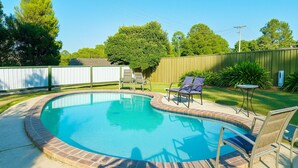 A circular swimming pool with a brick border, surrounded by a grassy yard and a wooden fence. - Eildon Lake Motel (Eildon)