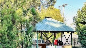 A covered outdoor area with a metal roof, a brick structure, and a grill. - Eildon Lake Motel (Eildon)