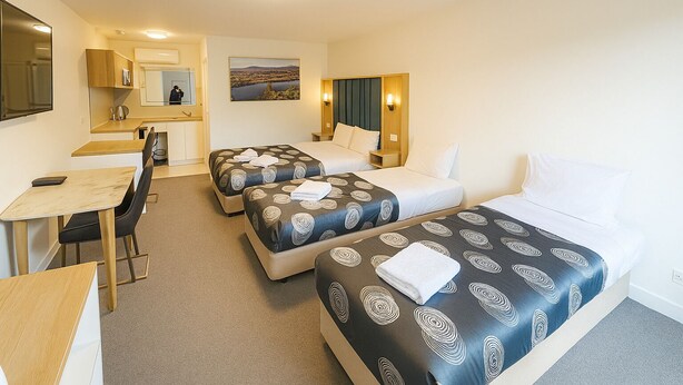 A hotel room with two beds, a desk, and a chair. - Eildon Lake Motel (Eildon)