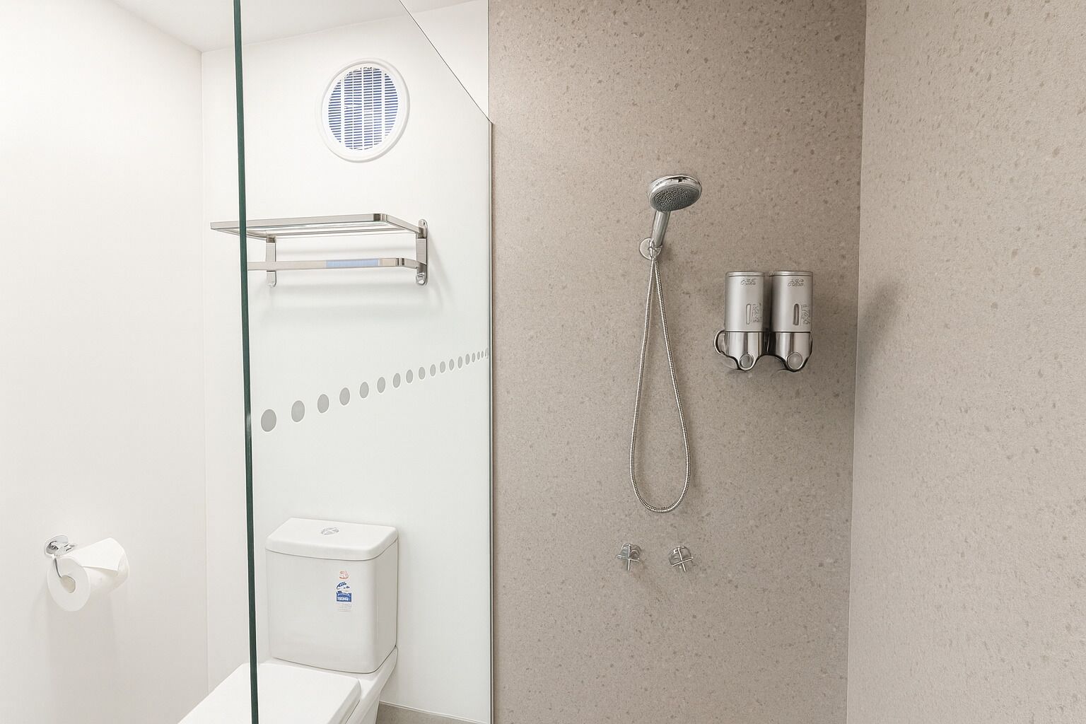 Een moderne badkamer met een douchecabine van glas, een toilet en een handdoekhouder.