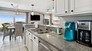 Une cuisine moderne dotée de plans de travail en granit, d’appareils électroménagers en acier inoxydable et offrant une vue sur l’extérieur.