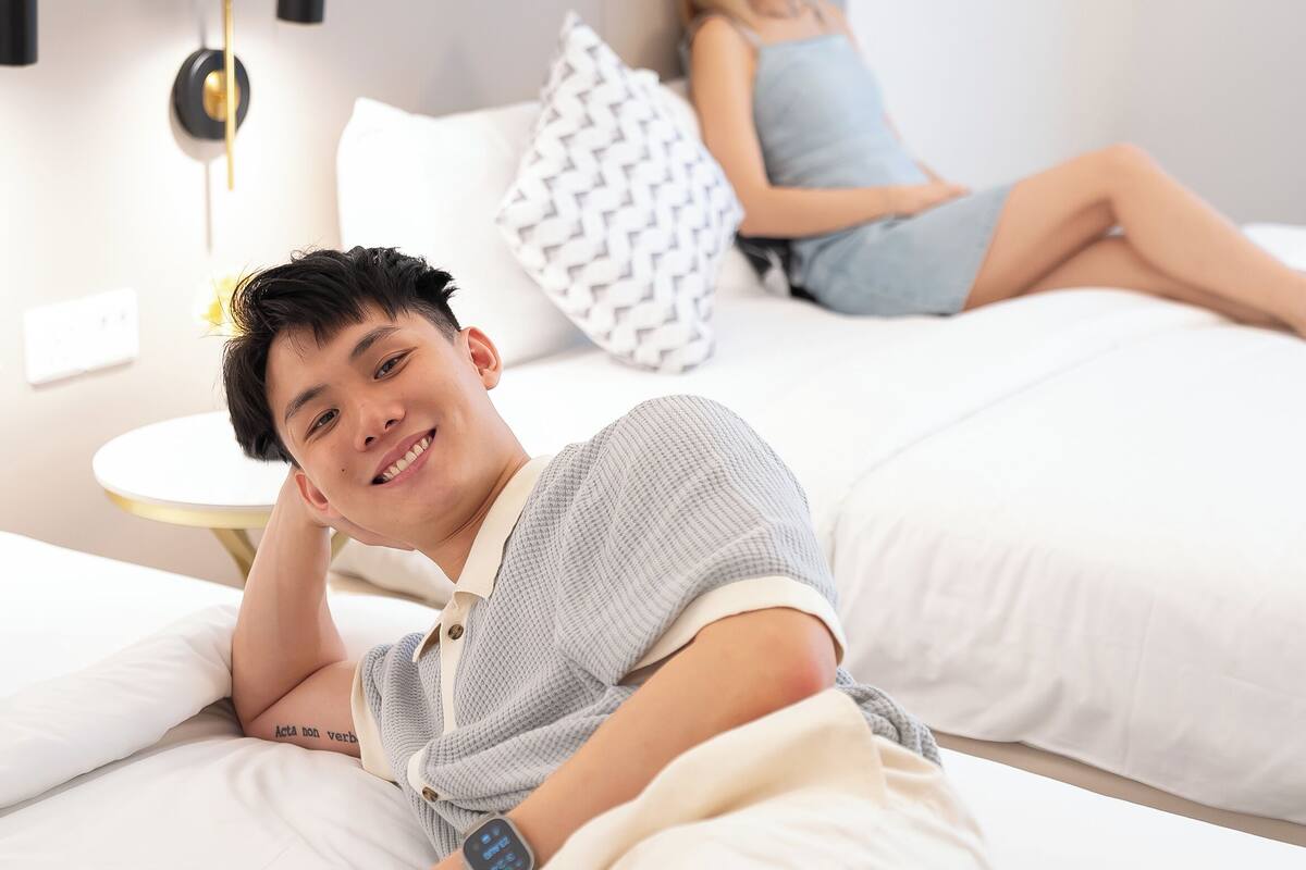 Un dormitorio con cama, mesita de noche y lámpara de pared.