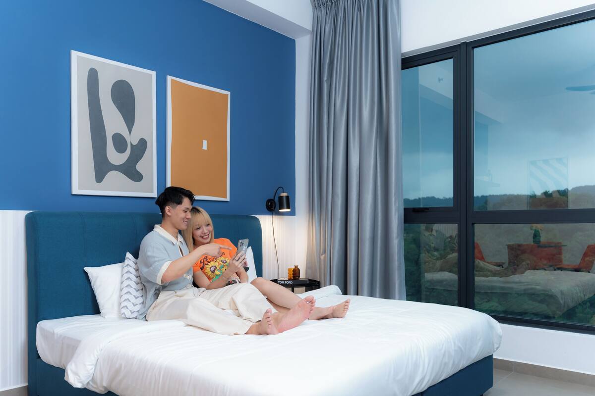 Un dormitorio moderno con una cama grande, vistas al exterior por una ventana y una obra de arte en la pared.