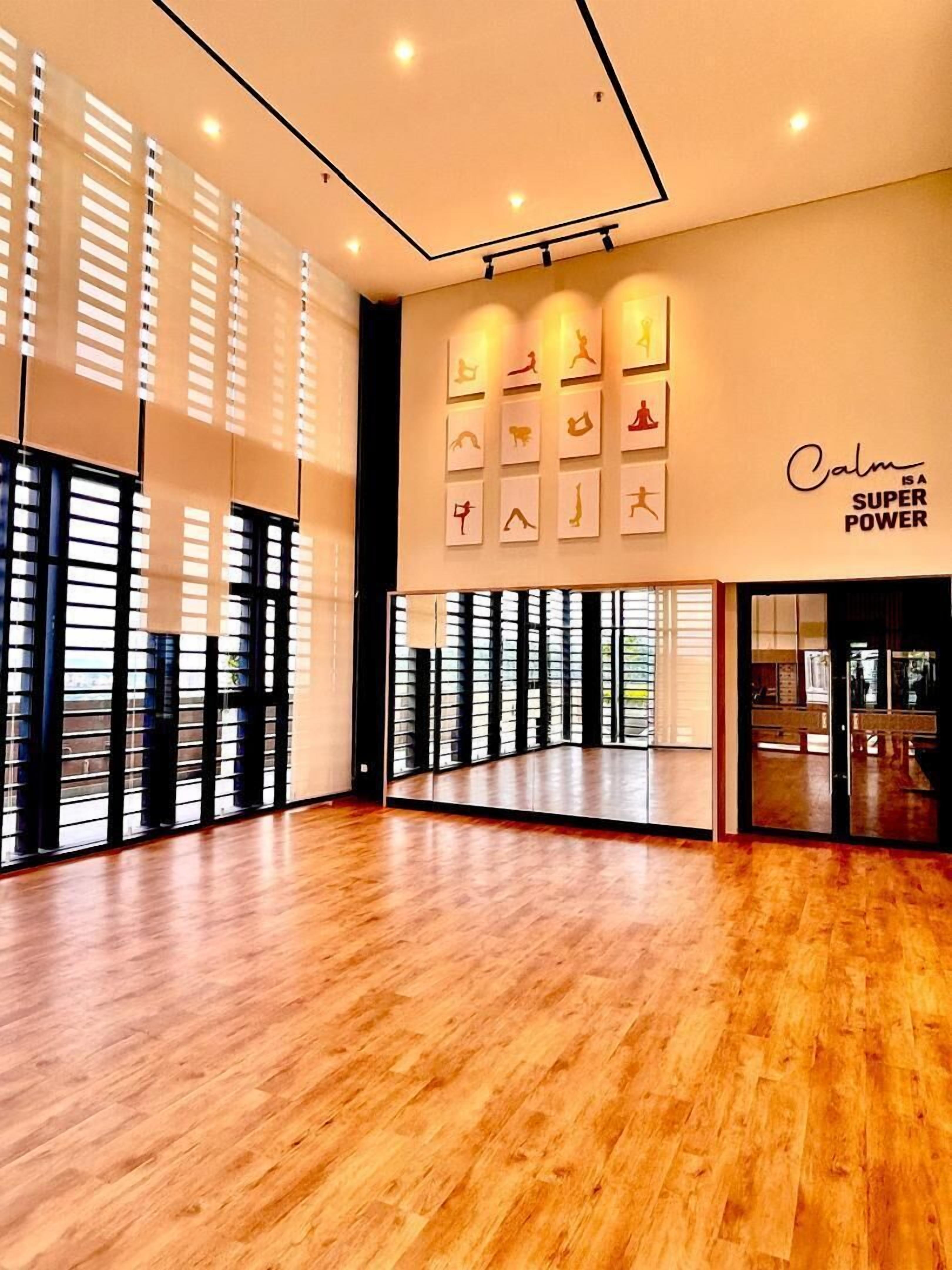 A spacious room with wooden flooring, large windows with blinds, and a wall with motivational posters and a 'Calm is a Super Power' sign.