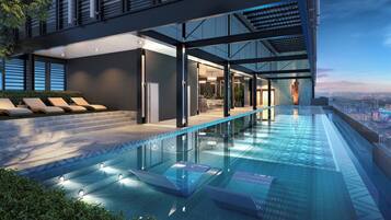 Um edifício moderno com piscina infinita no terraço, espreguiçadeiras e vista para a cidade.