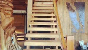 A wooden staircase with a carved figure on the left. - "Sleeps 15: Dog-Friendly Rustic Haven on Cortes Island" Large grass yard (Mansons Landing)