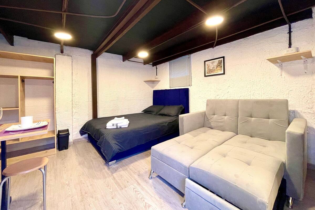 A bedroom with a bed, a desk, and a chair.
