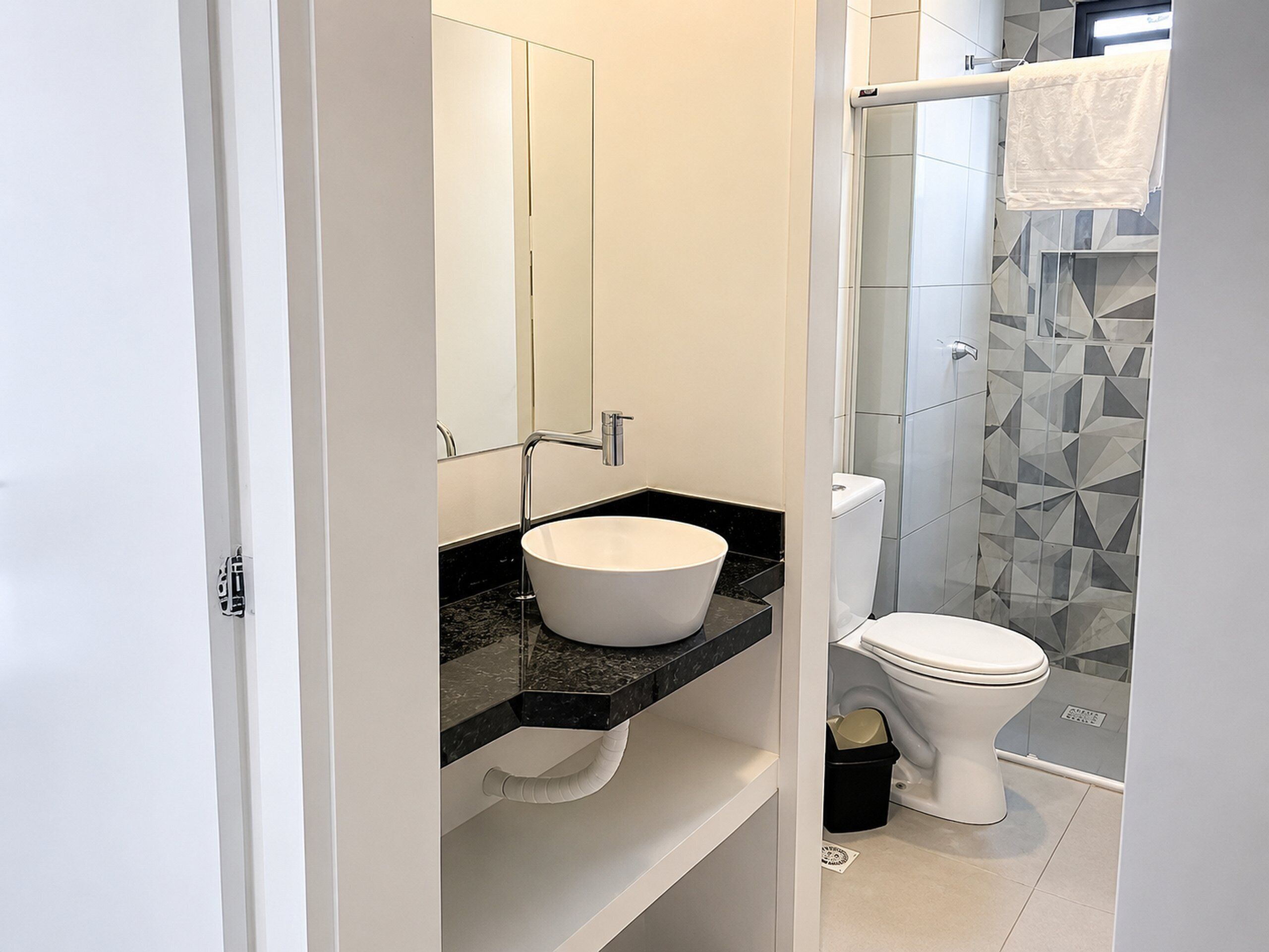 A modern bathroom with a white sink, a toilet, and a shower area.
