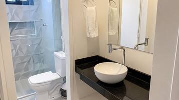 Un baño moderno con inodoro, lavabo y zona de ducha.