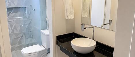 Un baño moderno con inodoro, lavabo y zona de ducha.