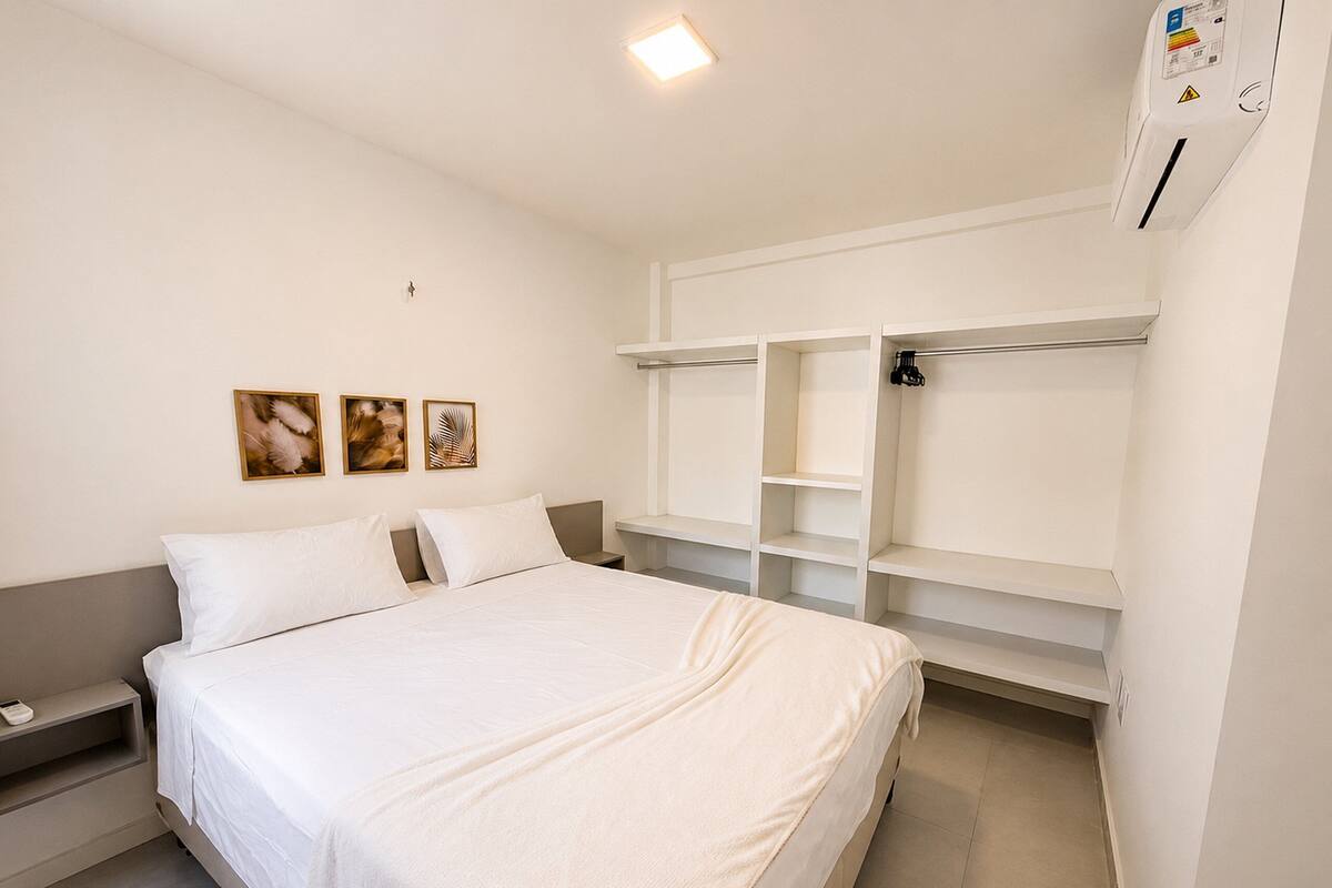 Quarto com cama, mesa de cabeceira, guarda-roupa e obras de arte nas paredes.