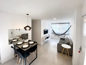 Un espacio de estar moderno con comedor, sofá, hamaca y televisor.