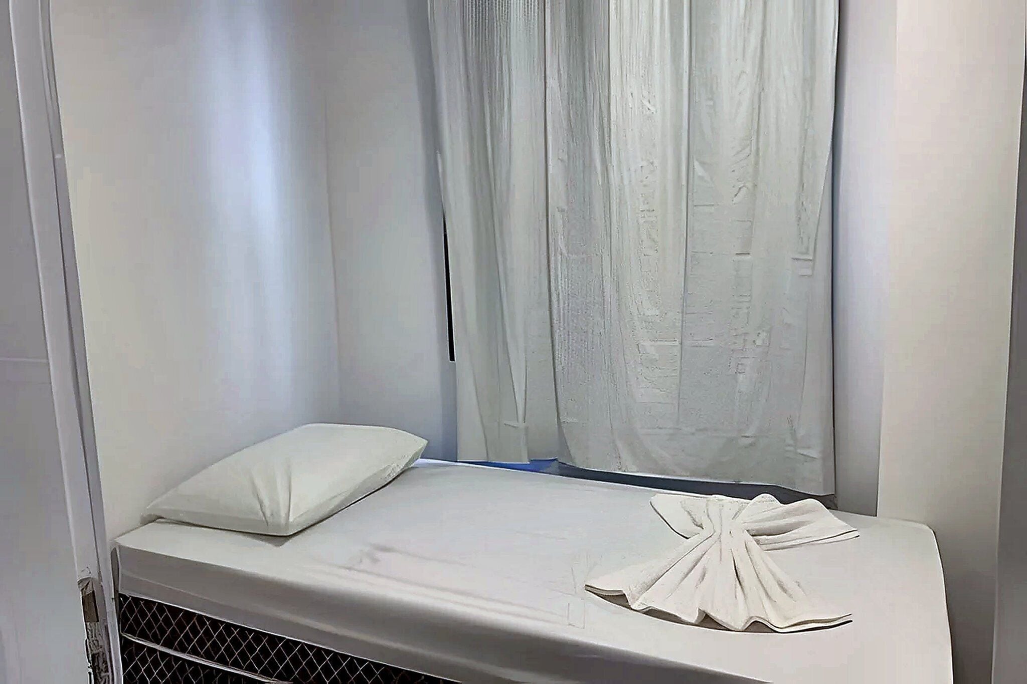 Una cama individual con un colchón, una almohada y una toalla blancos.