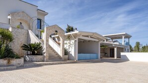 Ein modernes Haus mit einer Stein-Fassade, einem überdachten Außenbereich und einer Treppe, die zum Eingang führt.