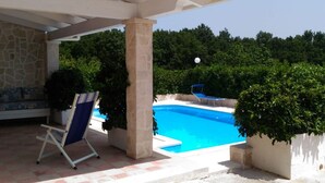 Ein Poolbereich mit klarem, blauem Pool, einer Liege und einer Pergola.