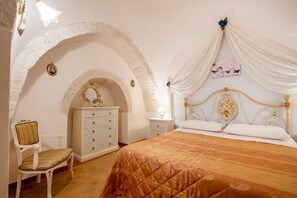 Una camera da letto con un letto, una sedia, una cassettiera e un arco che funge da porta.