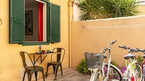 A small outdoor dining area with a table and chairs, a bicycle, and a plant.