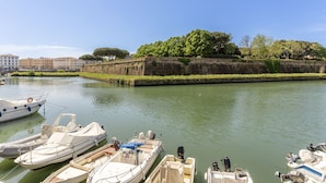 A canal with boats docked, a stone wall, and buildings in the background.