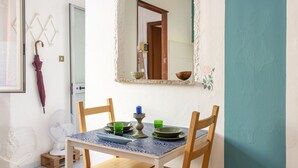 A dining area with a table set for two, a mirror, and a fan.