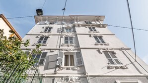 Un immeuble à plusieurs étages doté d’éléments architecturaux classiques, notamment des encadrements de fenêtres ouvragés et des moulures décoratives.