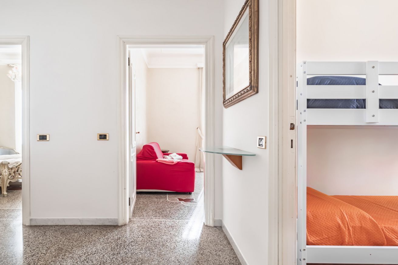 Ein Zimmer mit einem Etagenbett, einem roten Sofa, einer Glastrennwand und einem Spiegel an der Wand.