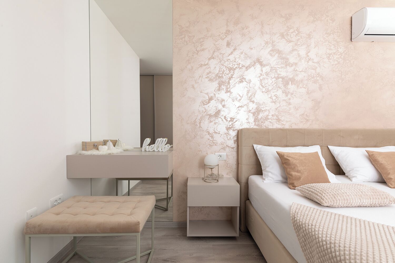 A modern bedroom with a bed, bedside tables, a vanity, and a bench.