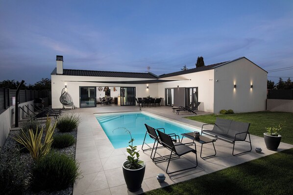Enjoy a relaxing stay in this home with a spacious backyard featuring a rectangular swimming pool and comfortable seating areas.