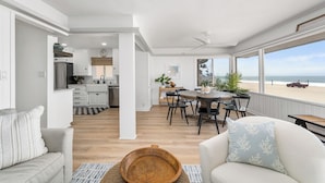Amplia sala de estar con cocina, comedor y un balcón con vista a la playa.