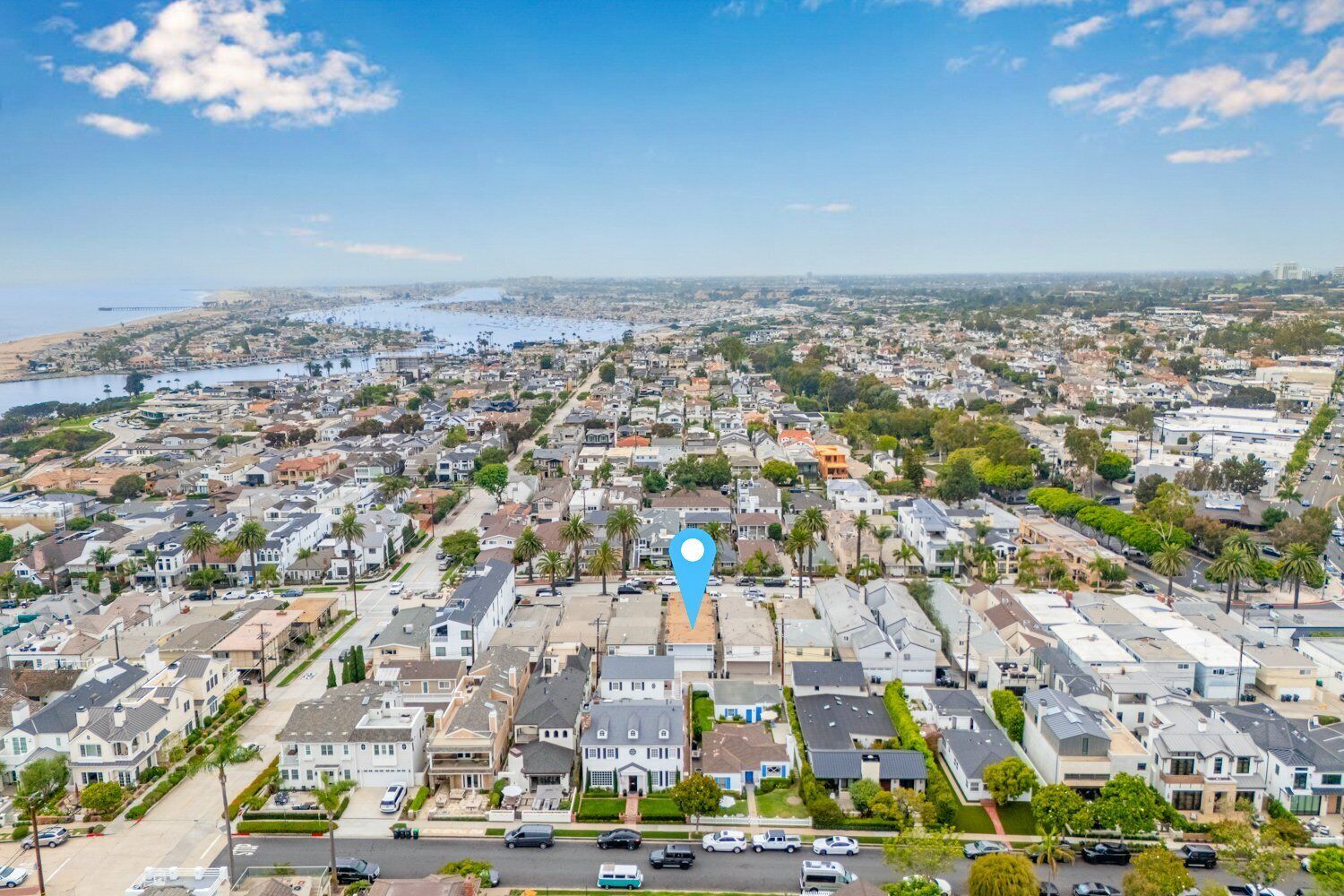 Et boligområde med enfamiliehuse og rækkehuse, en klar blå himmel og et vandareal i det fjerne.