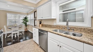 A modern kitchen with white cabinetry, granite countertops, and a stainless steel sink.