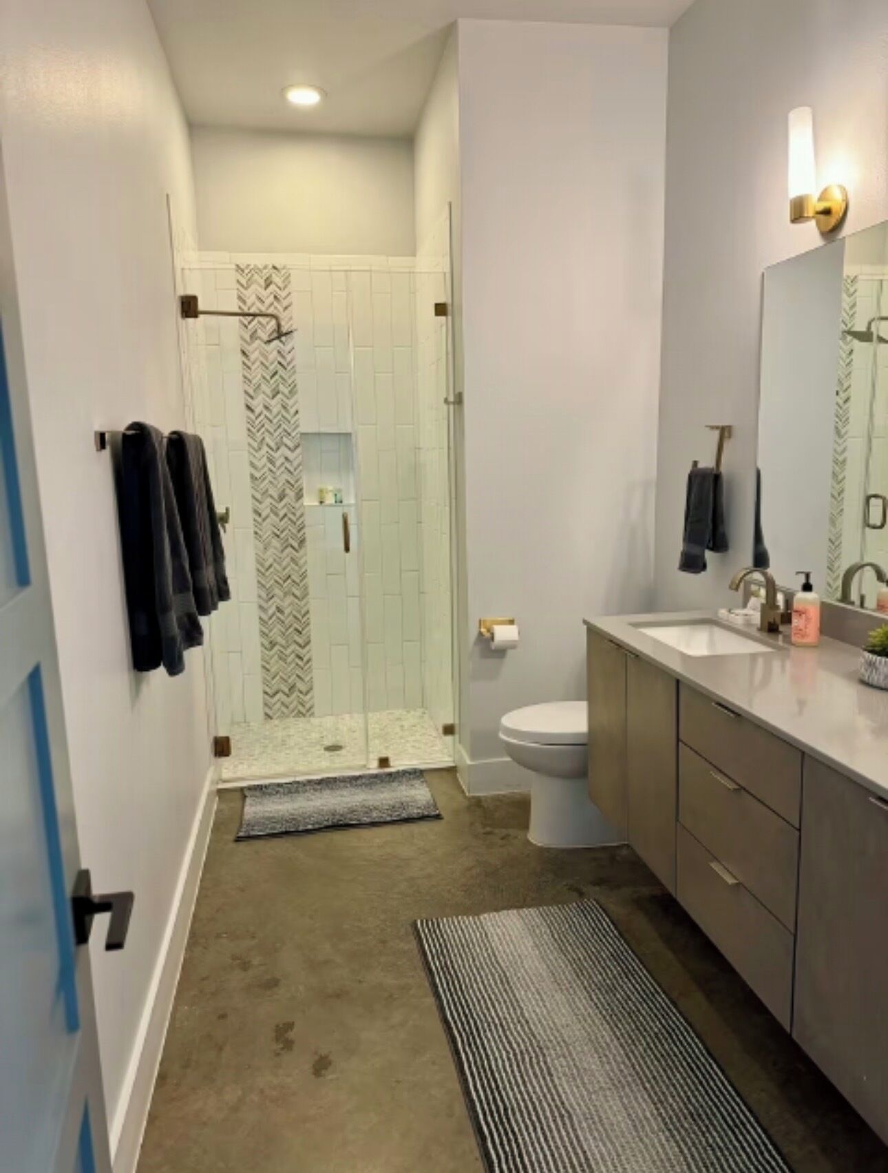 A modern bathroom with a shower, toilet, and vanity.