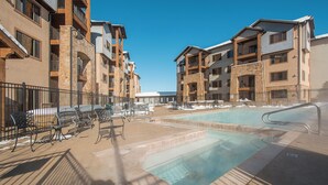 A hotel with a swimming pool, outdoor seating, and multiple balconies.