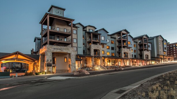 A multi-story hotel with balconies, a stone facade, and a well-lit entrance.