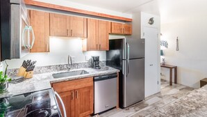 A modern kitchen with wooden cabinets, stainless steel appliances, a dishwasher, and a granite countertop.